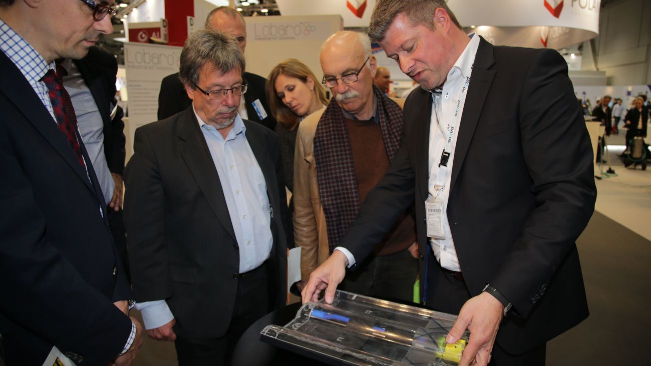 Mitarbeiter zeigt den Messebesuchern die Solardachpfanne