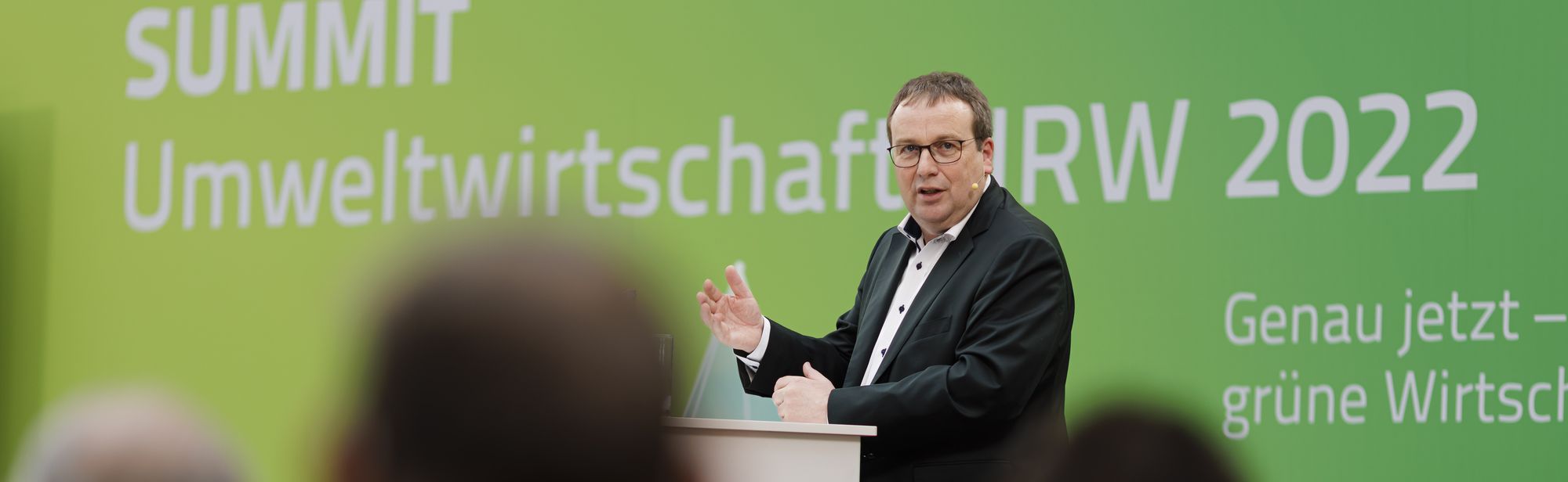 Minister Oliver Krischer am Rednerpult, im Hintergrund steht Summit Umweltwirtschaft 2022