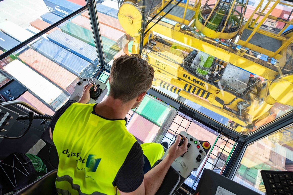 Mann blickt aus einem Hafenkran auf die Container