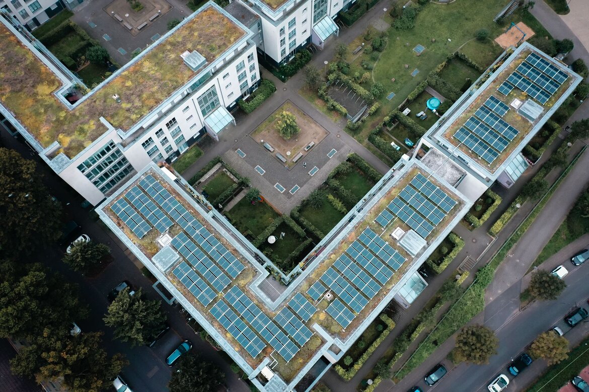 Blick von oben auf ein rechtwinkliges Gebäude mit Solaranlage auf dem Flachdach
