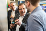 Minister Krischer im Gespräch am Gemeinschaftsstand, in der Hand hält er kleine Plastikteile