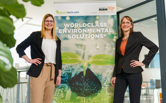 Zwei Frauen stehen neben einem Werbebanner mit der Aufschrift worldclass enviromental solutions