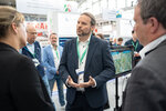 Ein Mann erläutert Ministerin Neubaur und Minister Krischer etwas am Messestand