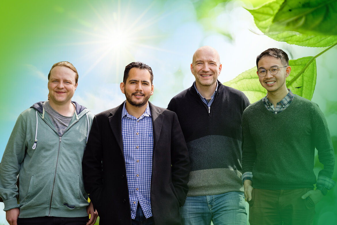 Gruppenbild: Vier Herren, im Hintergrund die Sonne und ein grünes Blatt