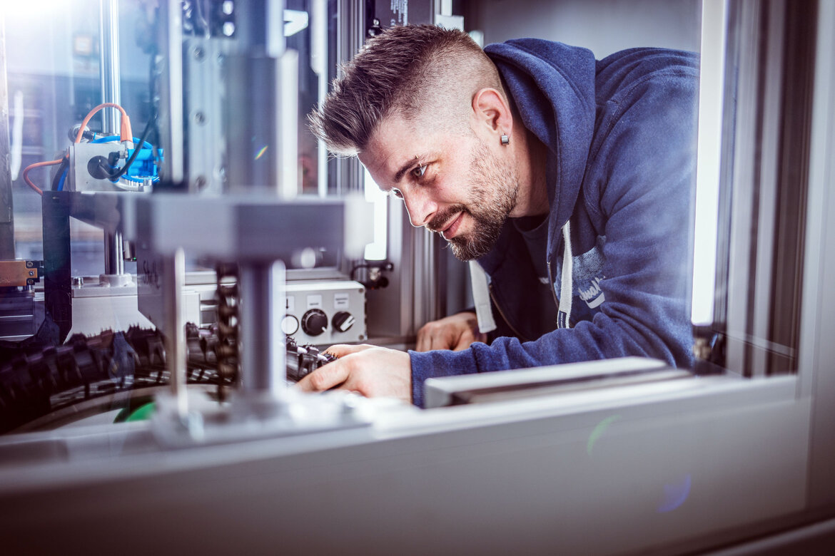 Ein Mann arbeitet mit einem Reifen unter einer Laborapparatur