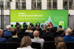 Eine Podiumsdiskussion auf einer Bühne mit grünem Hintergrund