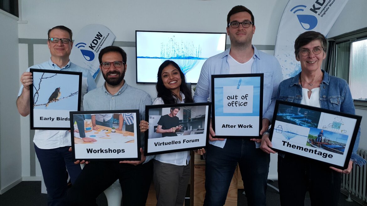 Teilnehmende eines Workshops präsentieren die Schilder „Early Bird“, „Wokshops“, „Virtuelles Forum“, „After Work“ und „Thementage“