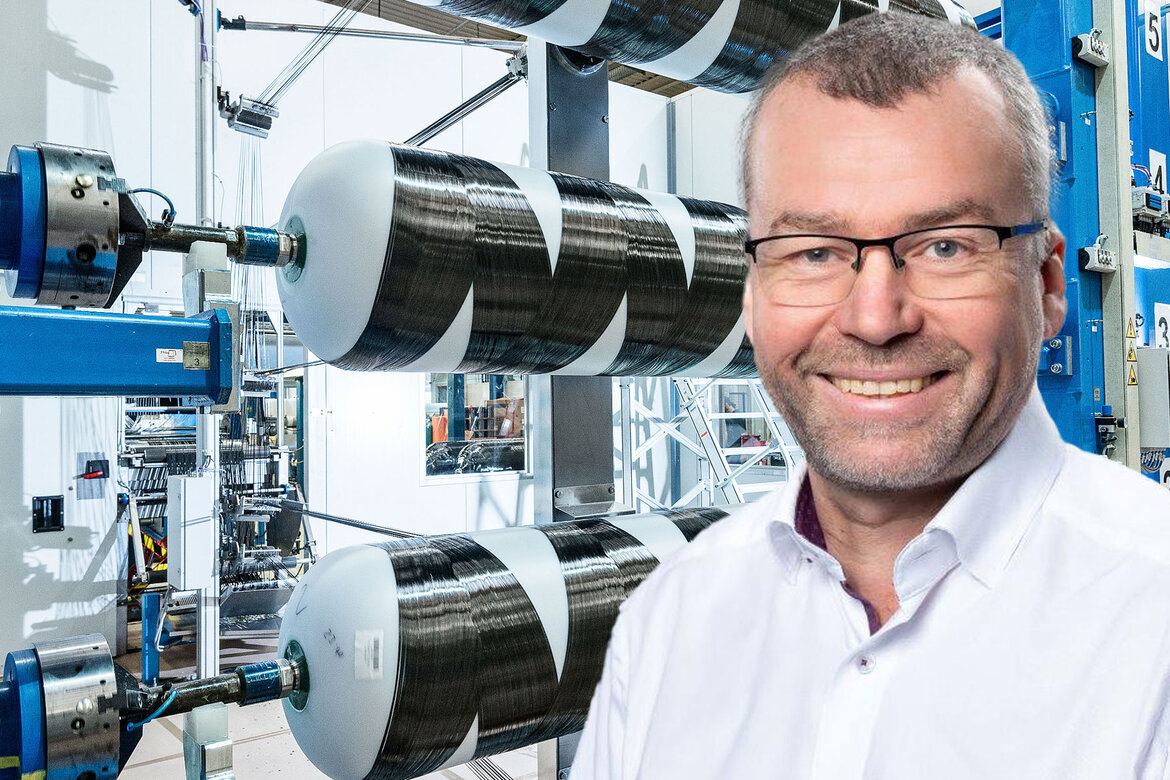 Ein Portrait von Wolfgang Wolter, im Hintergrund eine Maschine, die Kohlefasern zu Druckbehältern wickelt