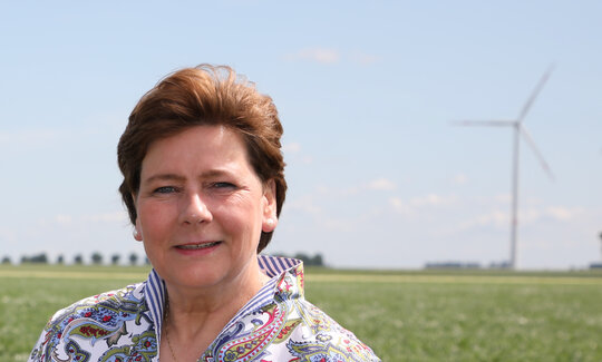 Portraitfoto Maria Kremer, im Hintergrund ein Windrad auf einem Feld