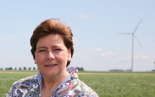 Portraitfoto Maria Kremer, im Hintergrund ein Windrad auf einem Feld