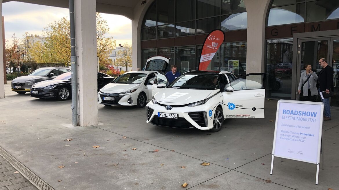 Drei Wasserstofffahrzeuge vor einem Konferenzgebäude