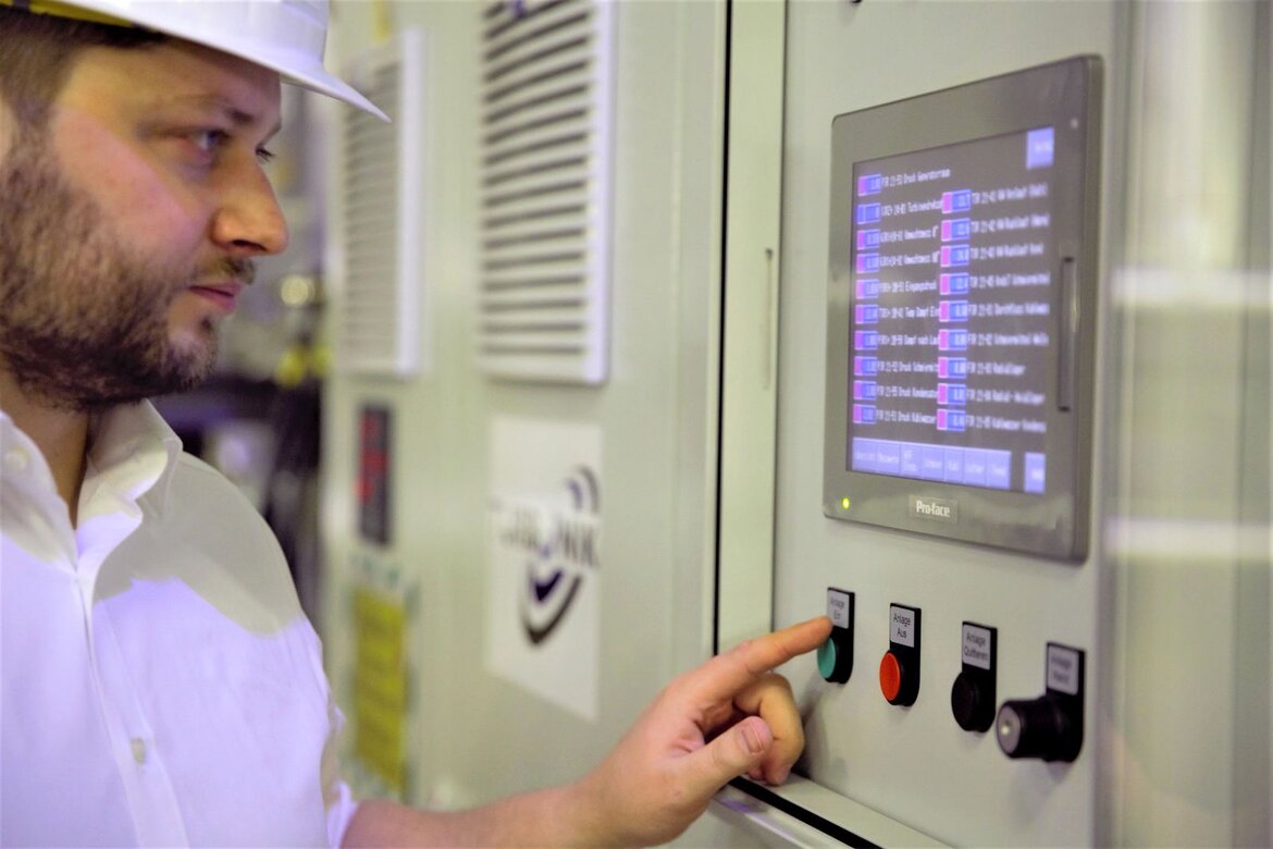 Ein Mann mit Bauhelm drückt einen Knopf an einem Terminal