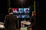 Blick über die Schulter auf einen Monitor, auf dem die 10 Nominierten zu sehen sind