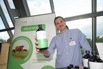 Ein junger Mann hält eine Flasche mit Naturdünger in die Kamera