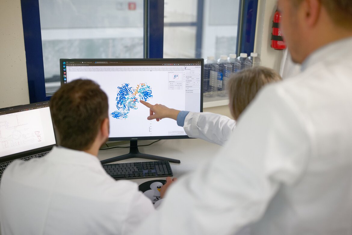 Mehrere Personen in einem Labor betrachten eine Struktur auf einem Computermonitor