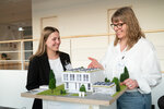 zwei Frauen an einem Modellhaus mit Solarpanelen auf dem Dach