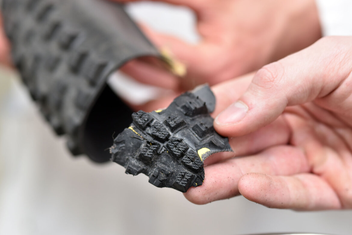 Eine Hand hält ein Stück zerkleinerten Reifen