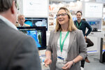 Eine junge Frau am Gemeinschaftsstand, im Hintergrund verschiedene Monitore
