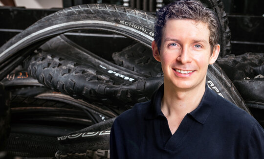 Ein Portrait von Felix Jahn vor einem Stapel alter Fahrradreifen
