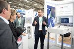 Ein Mann erläutert Ministerin Neubaur und Minister Krischer etwas am Messestand