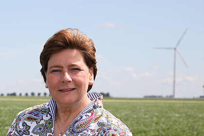 Portraitfoto Maria Kremer, im Hintergrund ein Windrad auf einem Feld